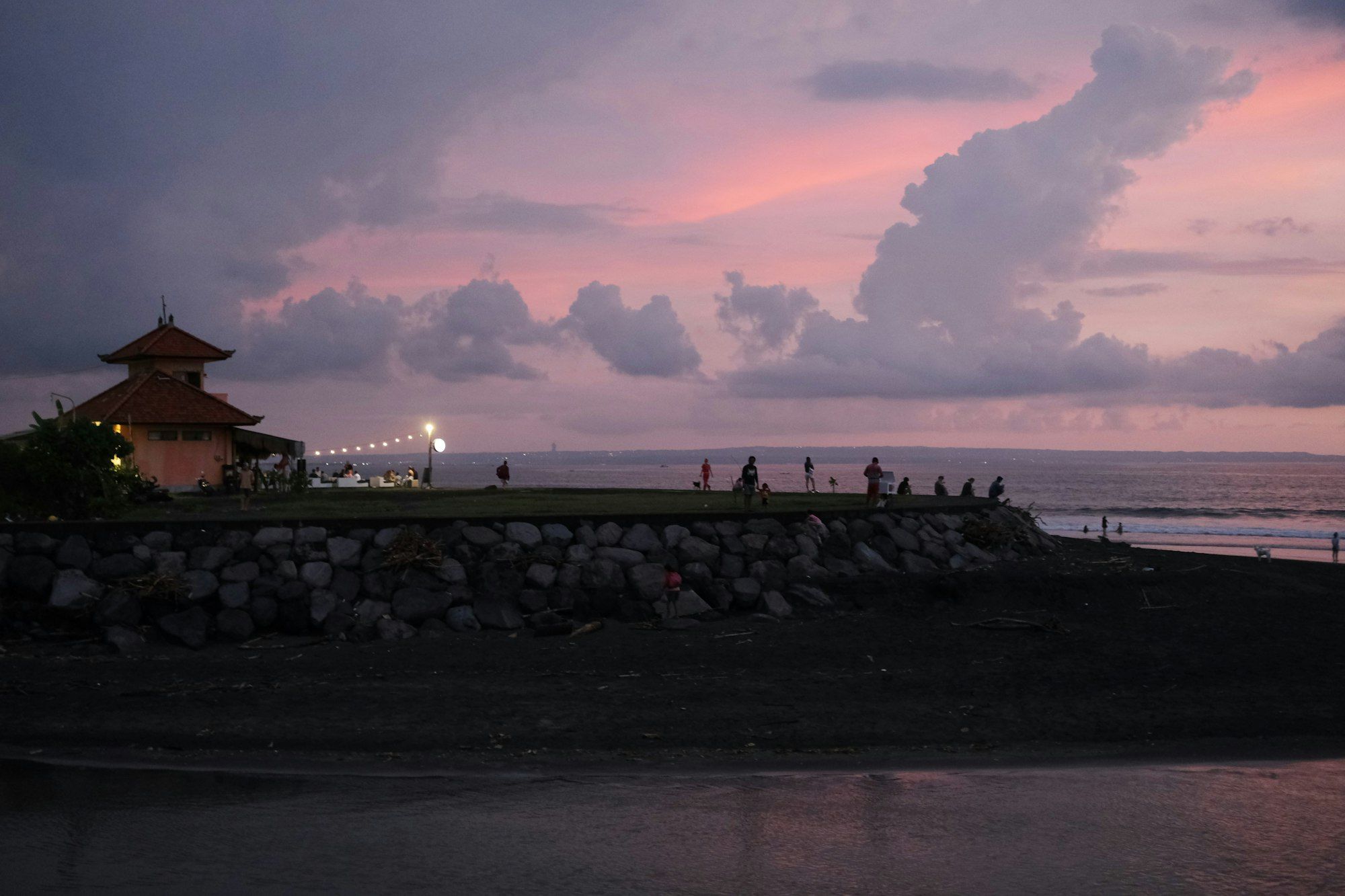 Awan merah muda menjelang malam di atas tanggul batu di tepi pantai